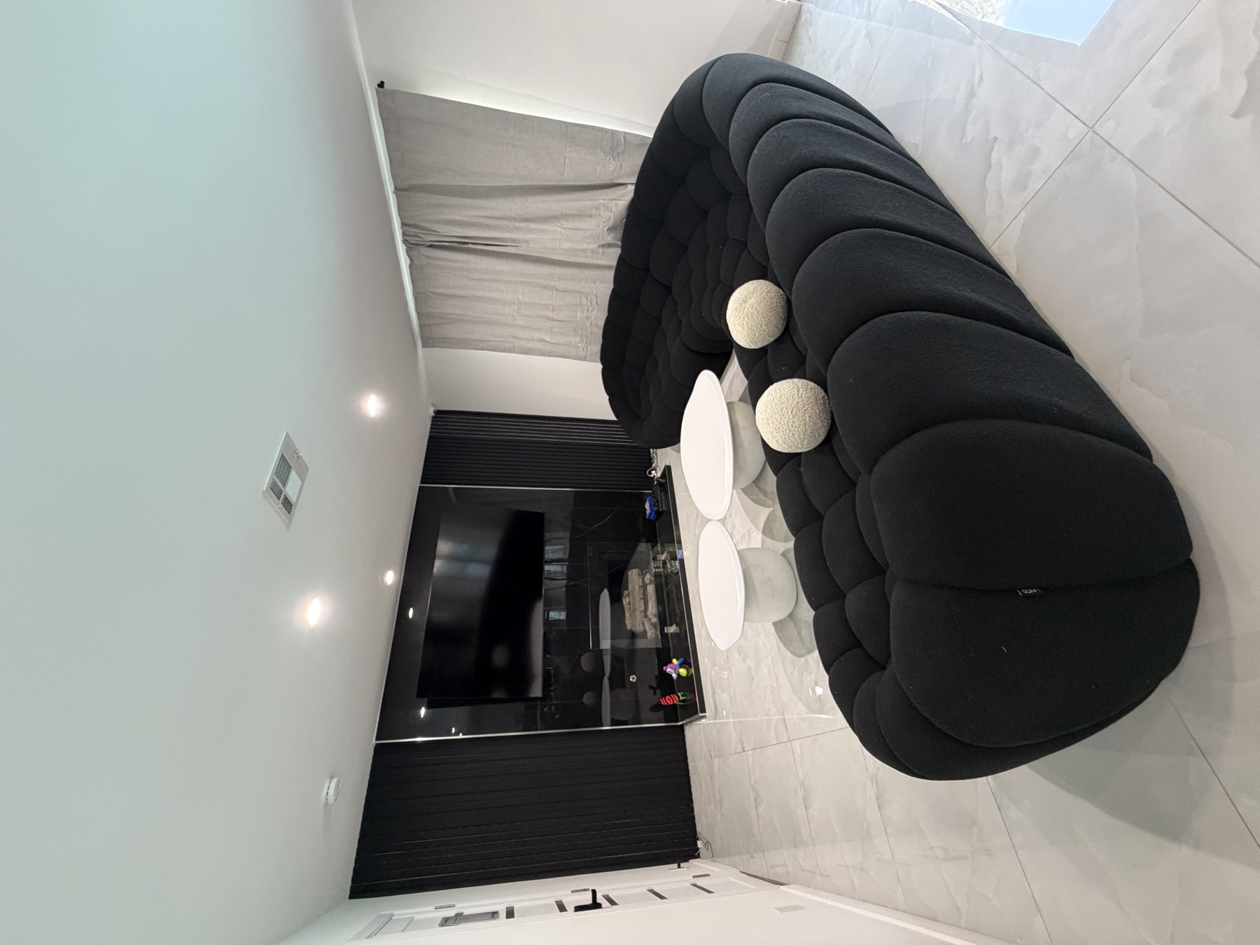 Lounge with a black curved sectional sofa and marble floors