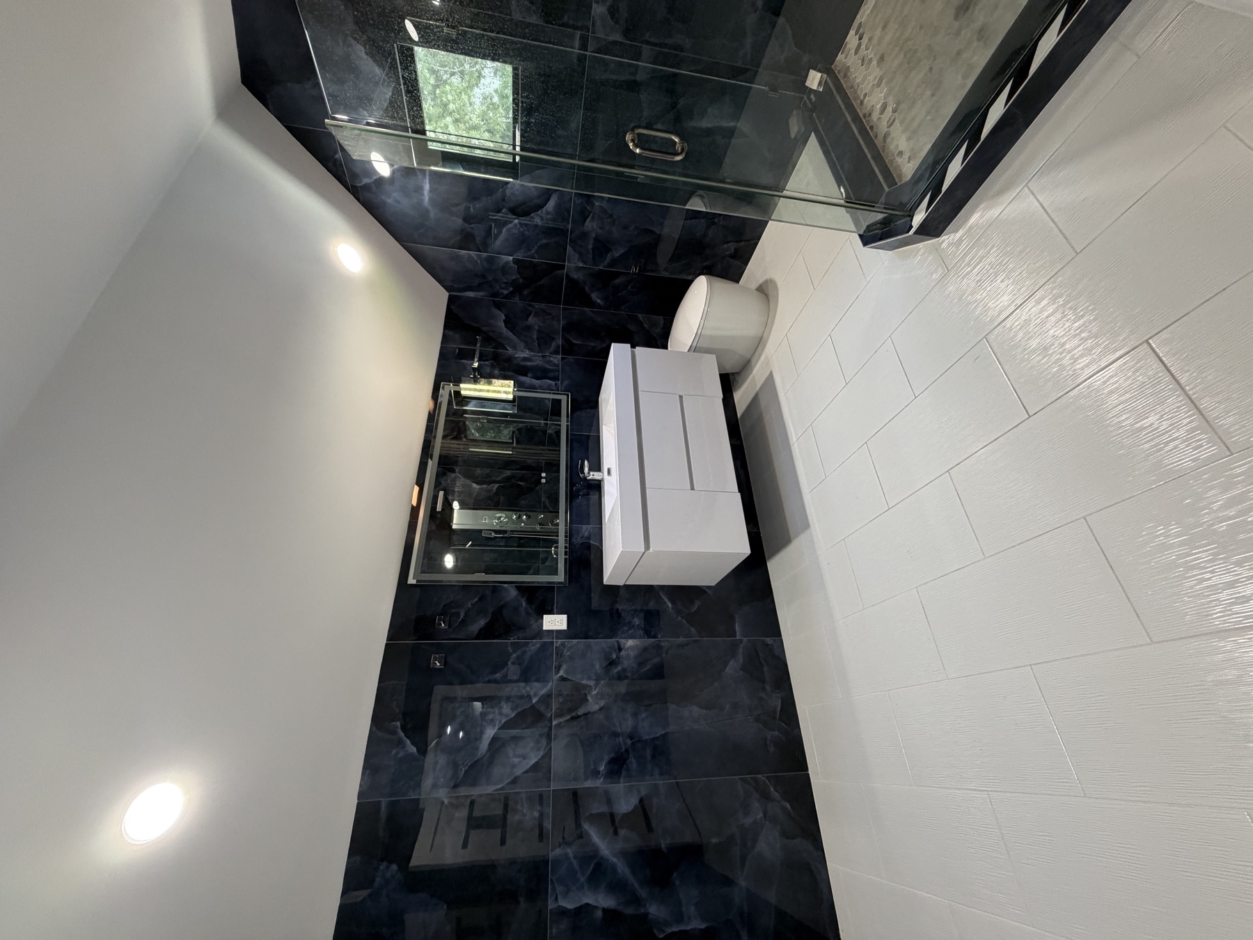 Bathroom with dark marble walls and glass shower